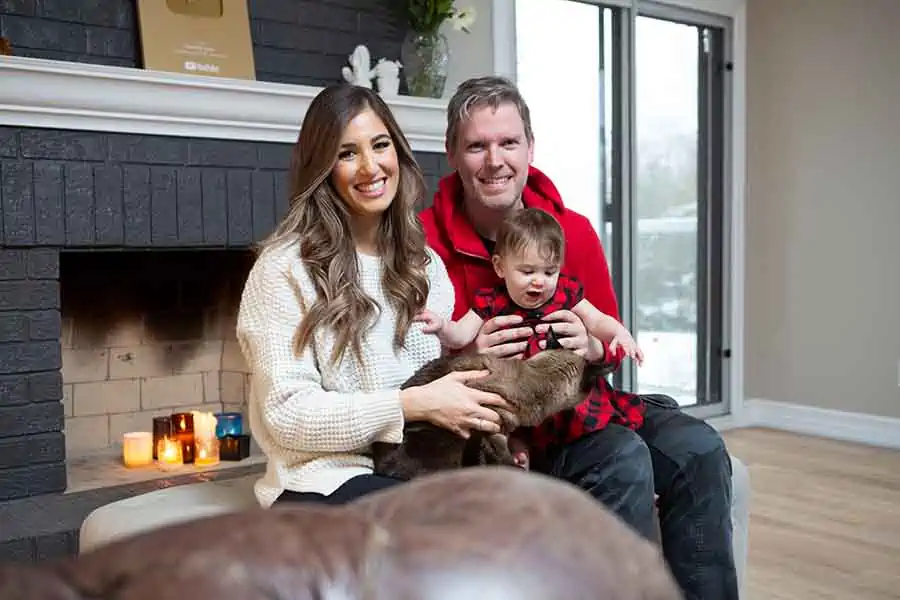 Melissa, Chad, and Riley sitting in front of the fireplace