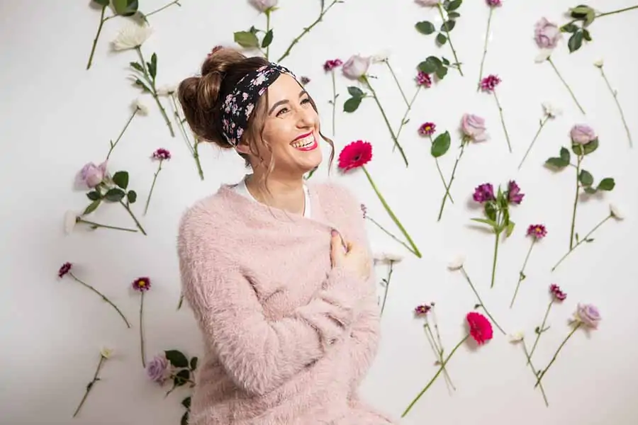 Melissa Maker sitting in front of a wall of flowers