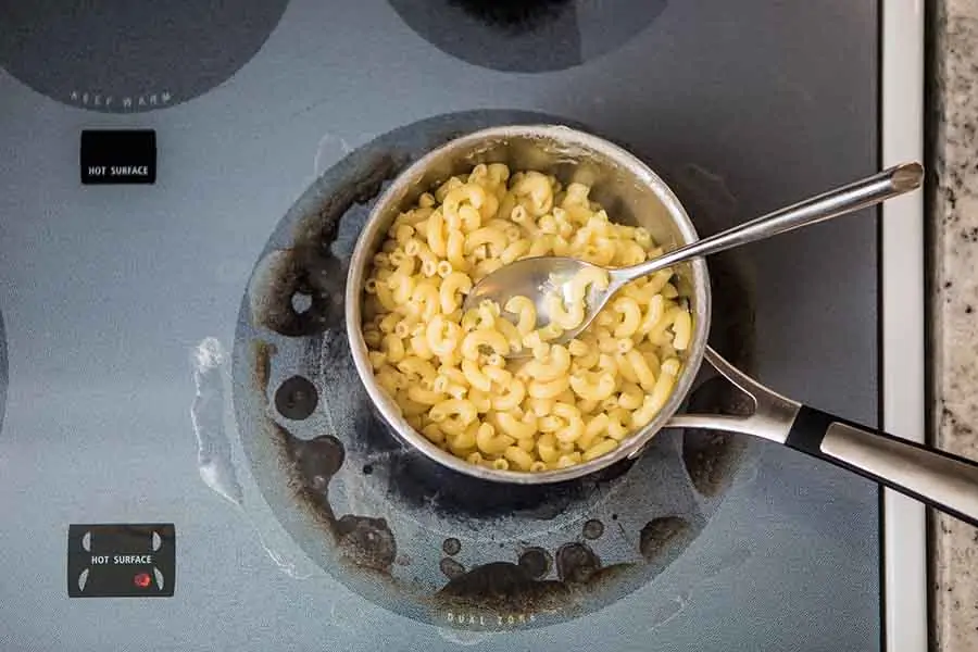 A pot on the stove full of pasta.