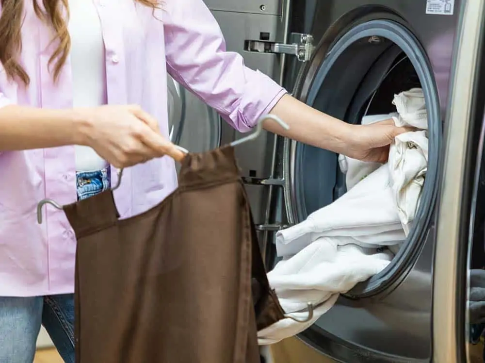 Melissa is putting a shower curtain into the washing machine