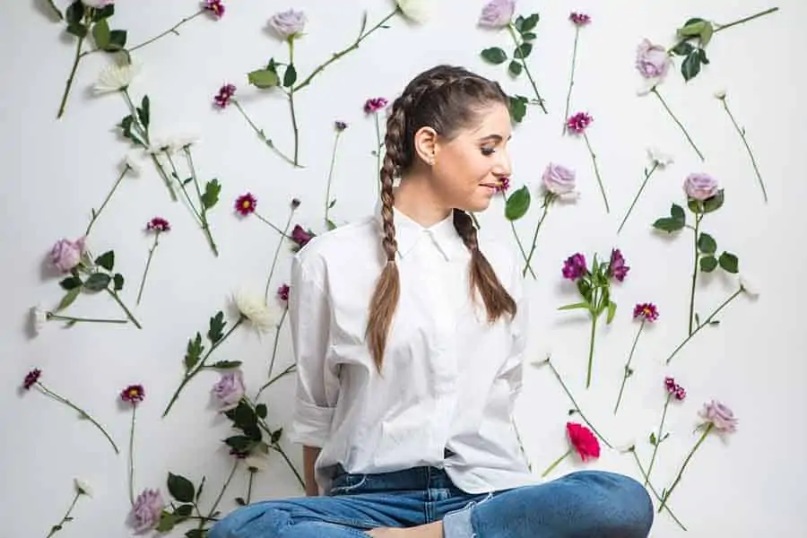 Melissa sitting against a wall of flowers